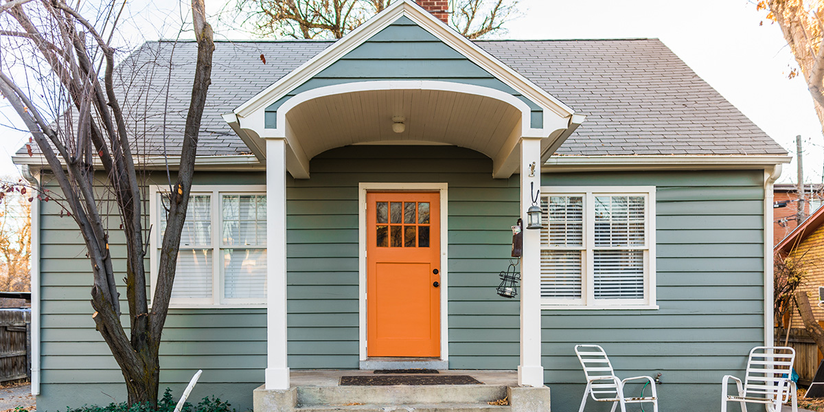 A green house with an orange door that was a fix and flip