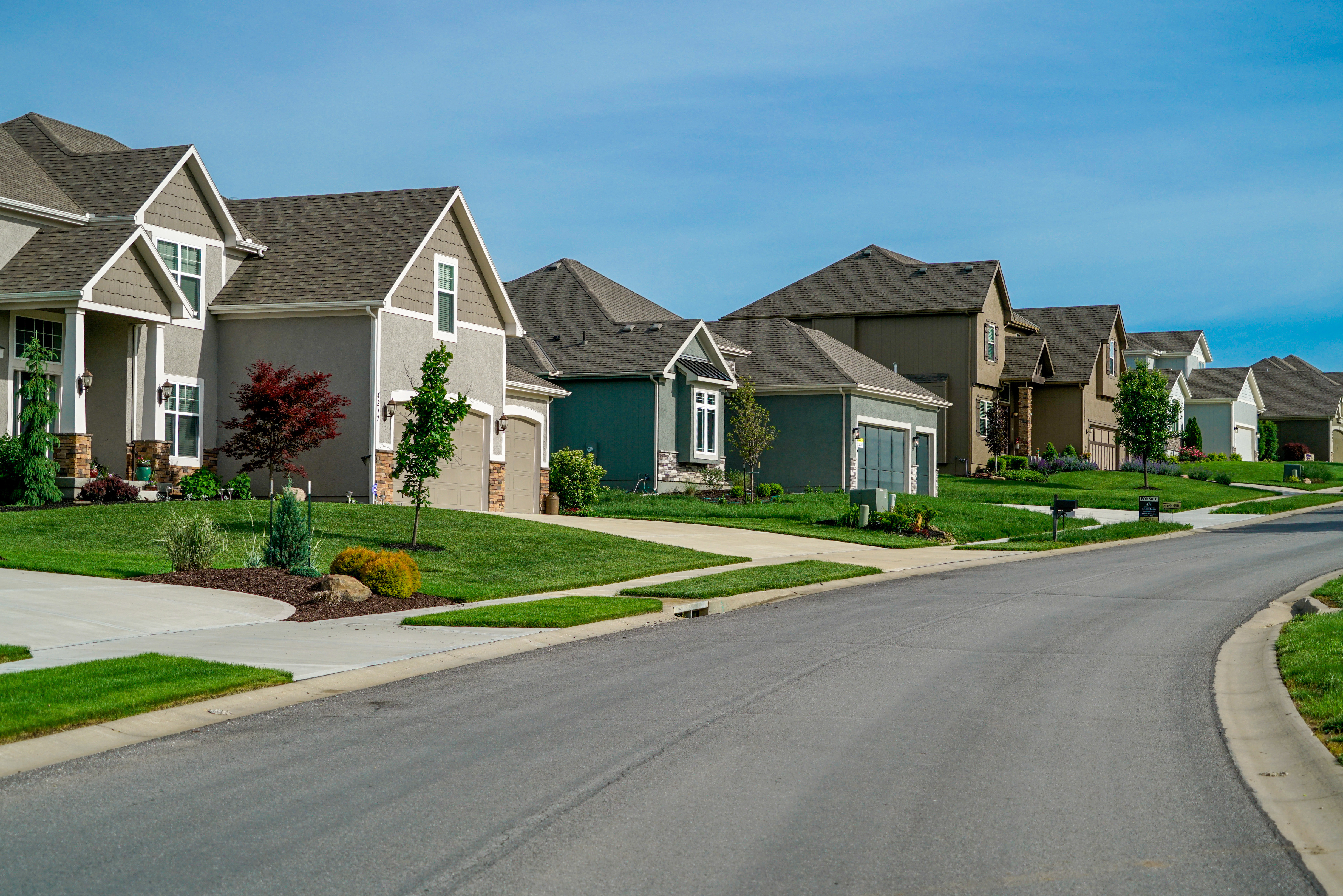 A clean street of real estate investing homes on a blue sky day.