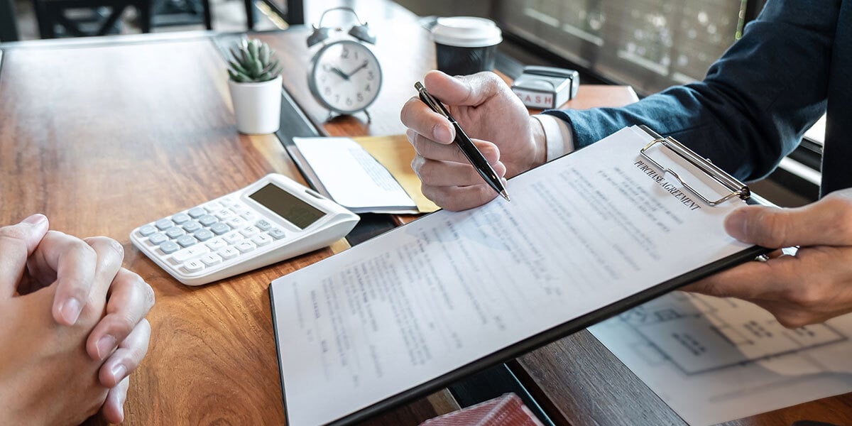 A man's hands showing paperwork that needs to be signed for real estate investing