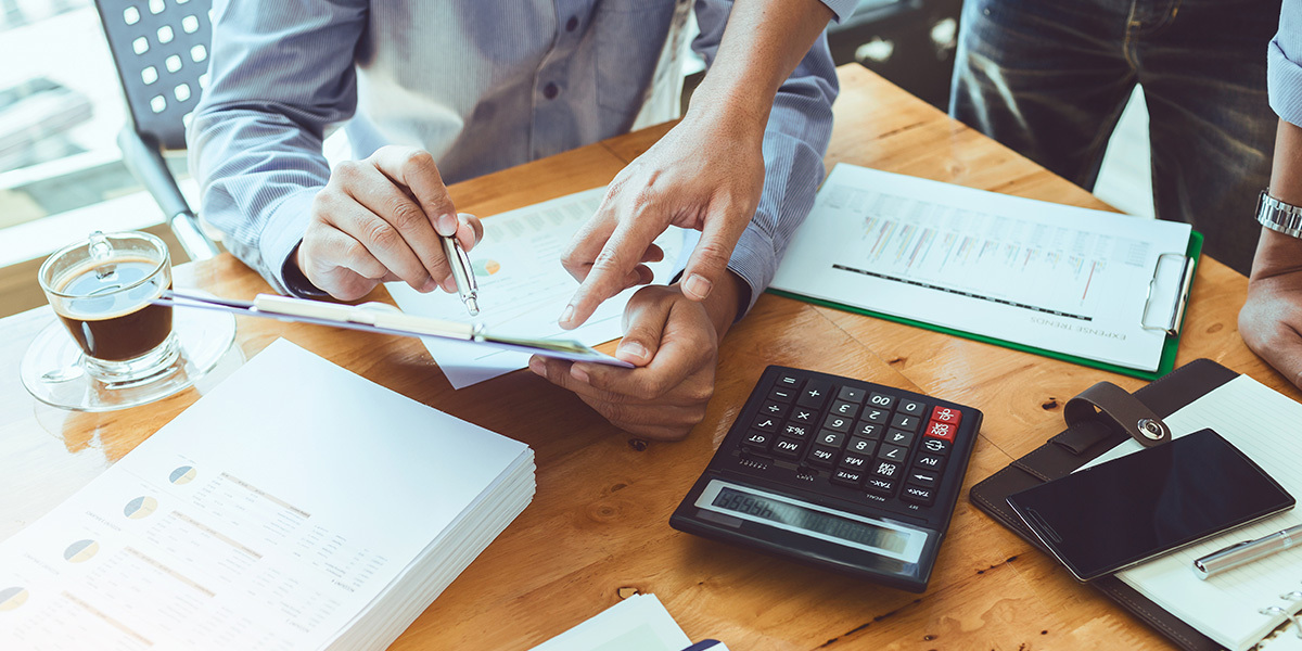 Two people looking over a real estate investing deal's numbers on a desk with a calculator