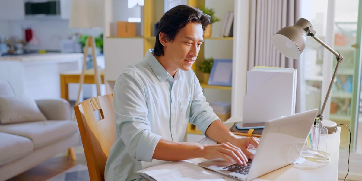 A man working from home on a laptop in a bright, modern apartment embodies the flexibility of the remote work revolution.