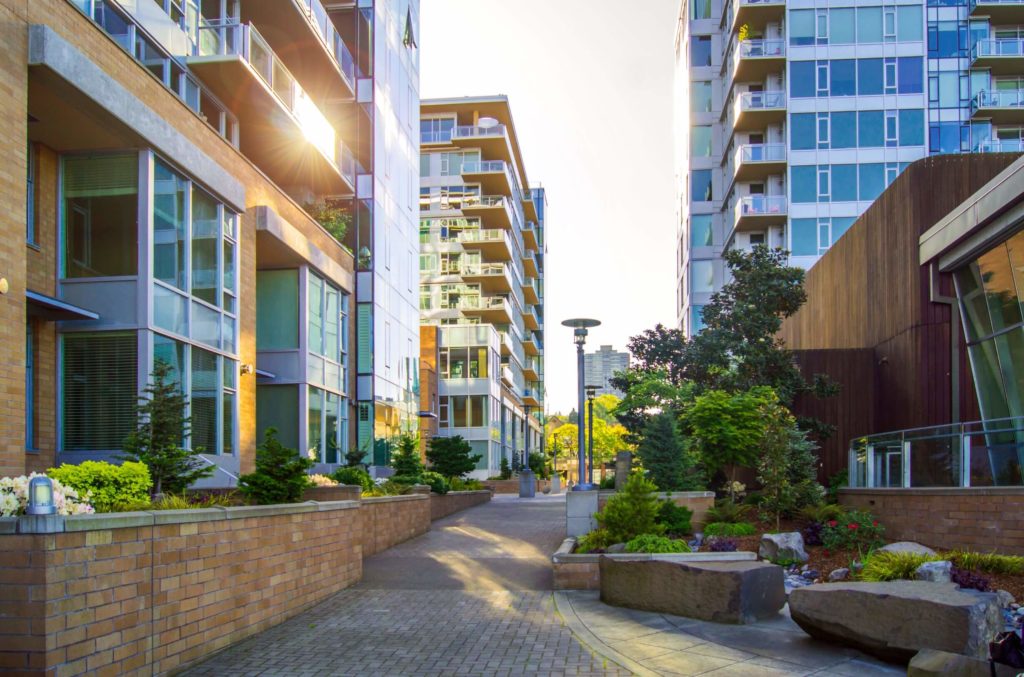 A pretty street between condos for real estate investing with greenery around it.