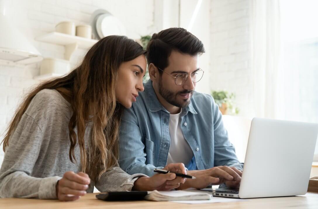 a husband and wife real estate investment team researching properties on a laptop