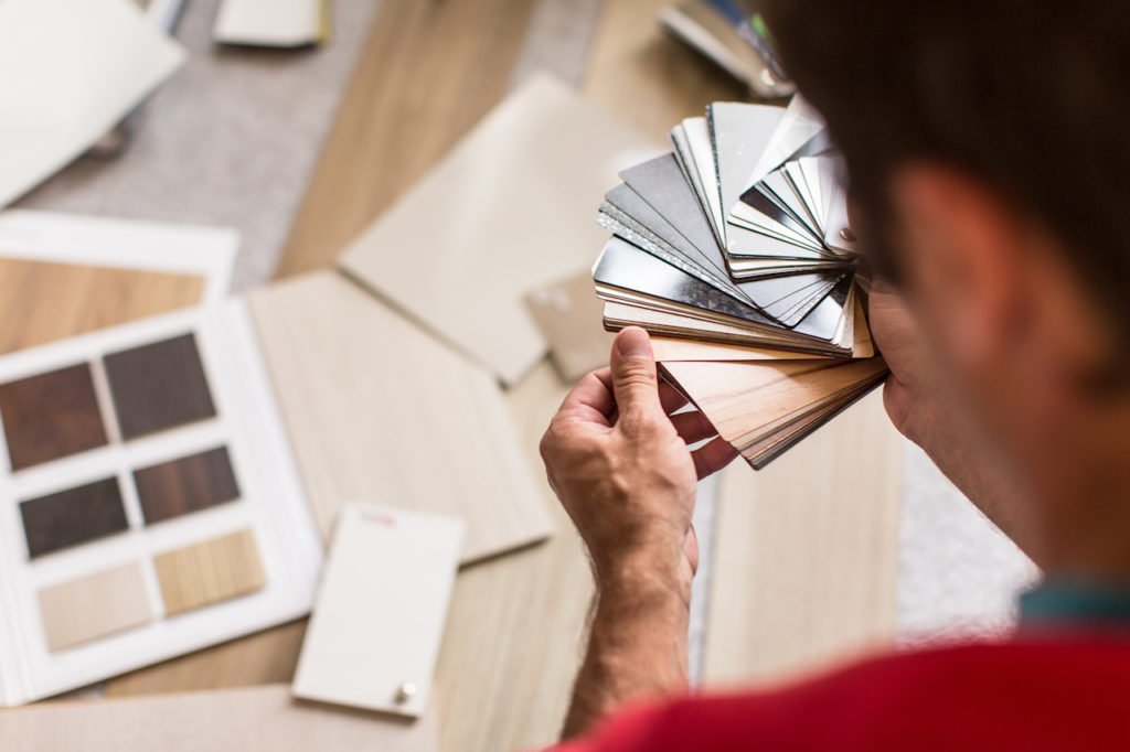 A person looking at paint swatches over a desk.