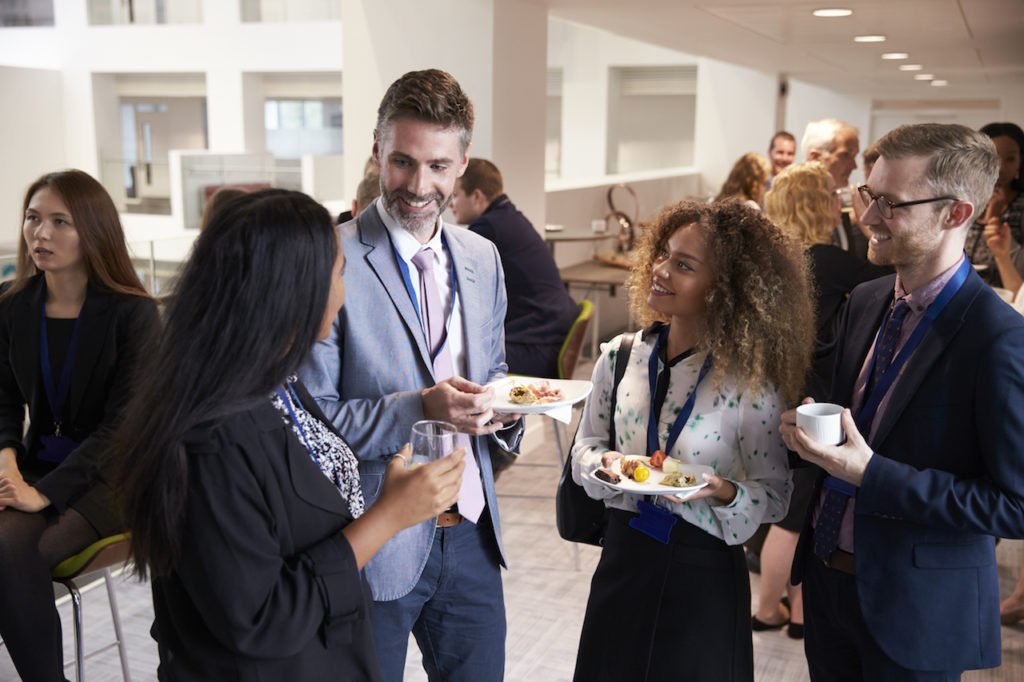 Two men and two women eating and talking at real estate investing event.