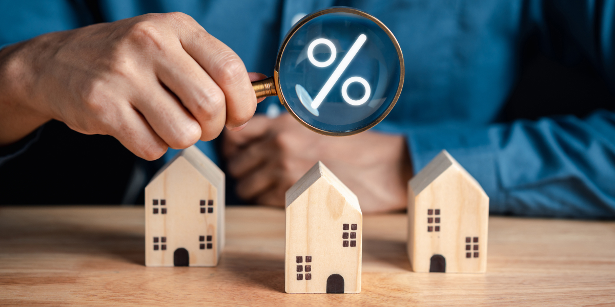 small wooden houses on a table with a percentage sign floating above them