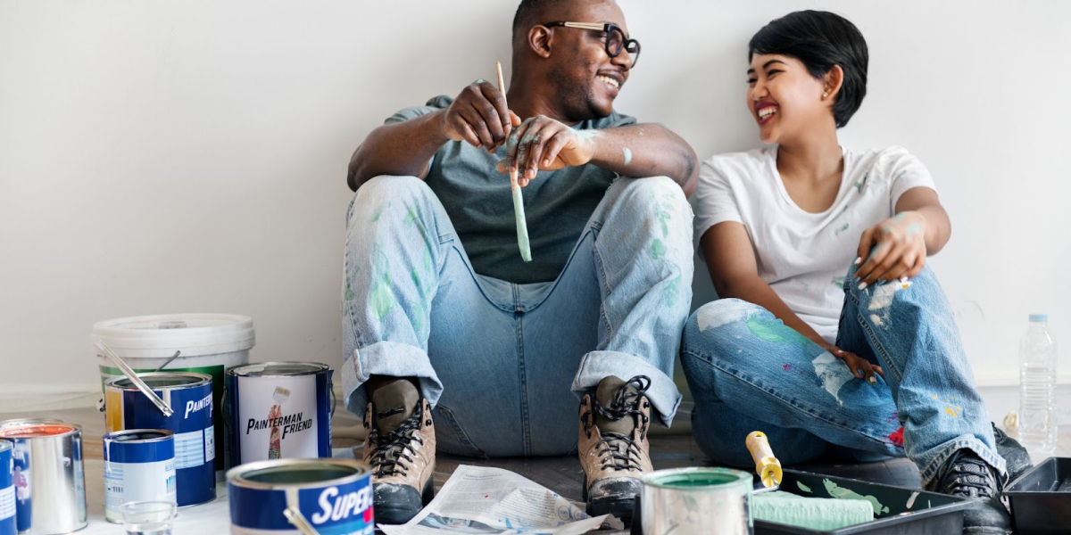 smiling couple real estate investors taking a break surrounded by paint cans