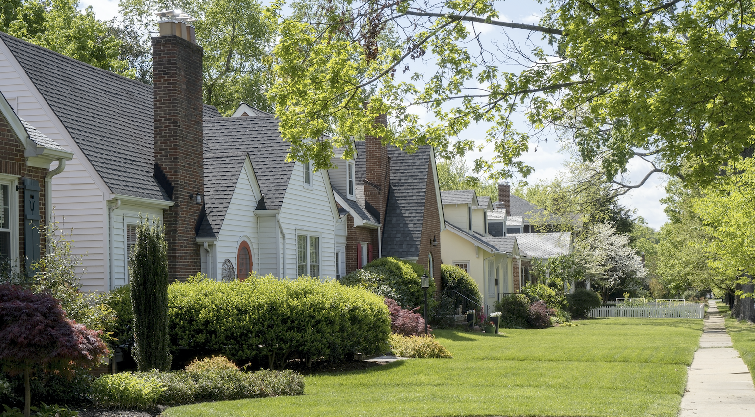 A idyllic neighborhood of homes with green grass and trees.